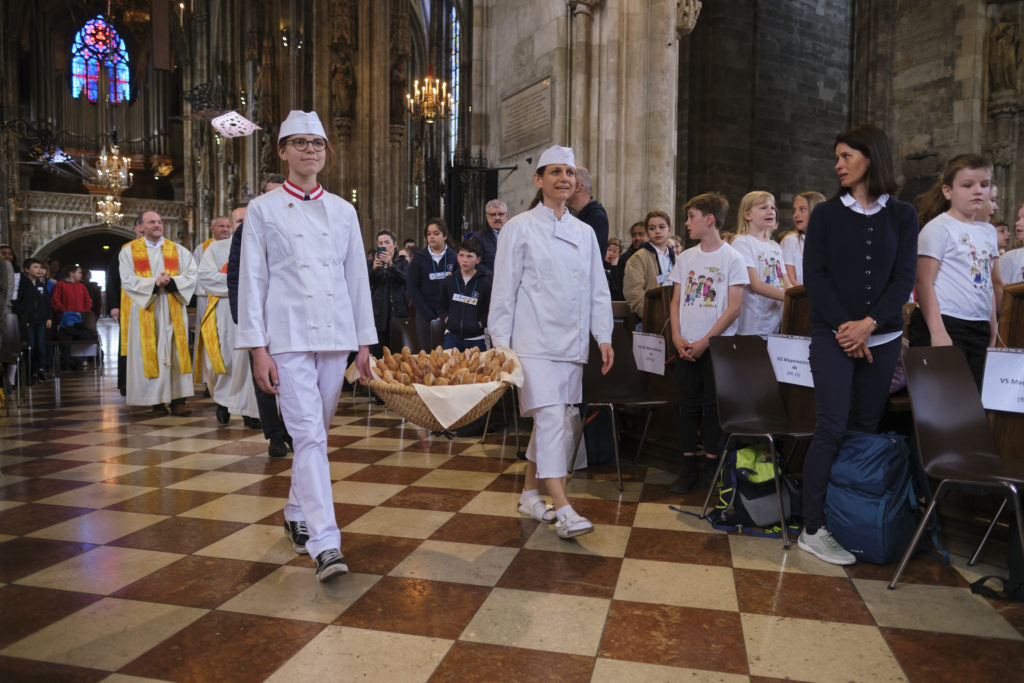 Lehrlinge der Bäckerei Grimm tragen einen Korb mit Klemensweckerl im Stephansdom